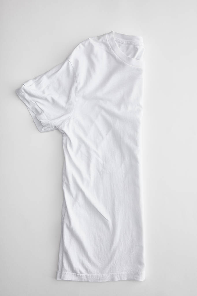 вид сверху пустой сложенной наполовину футболки на белом фоне
 - Фото, изображение