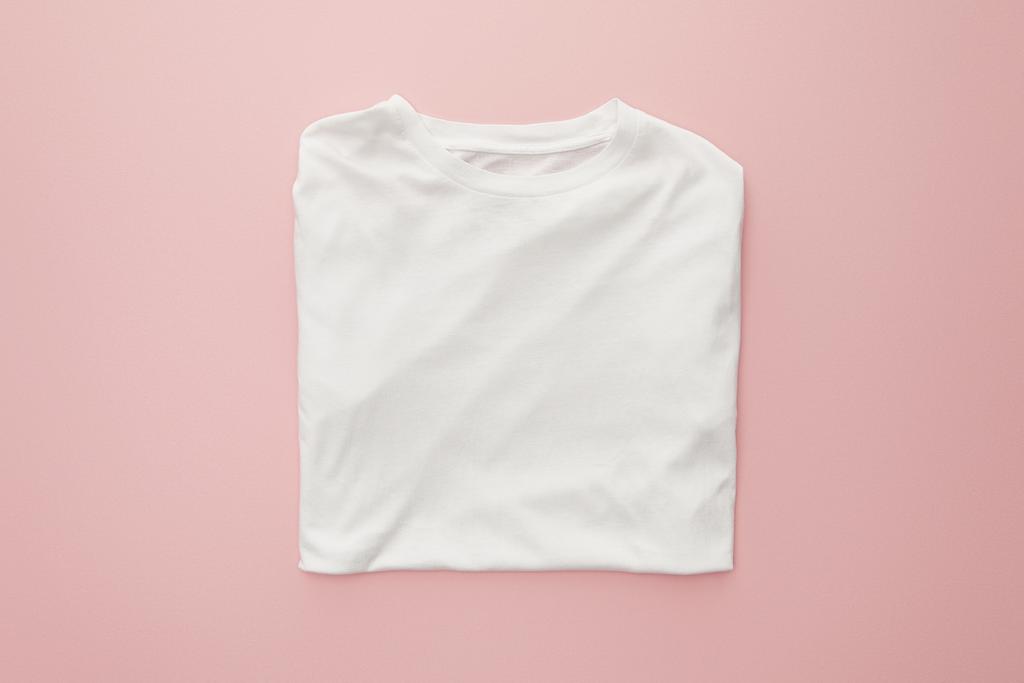 Widok z góry pustego białego, złożonego t-shirt na różowym tle - Zdjęcie, obraz