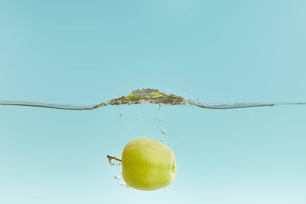 suda ıslatın ve kabarcıklar mavi zemin üzerine yeşil elma - Fotoğraf, Görsel