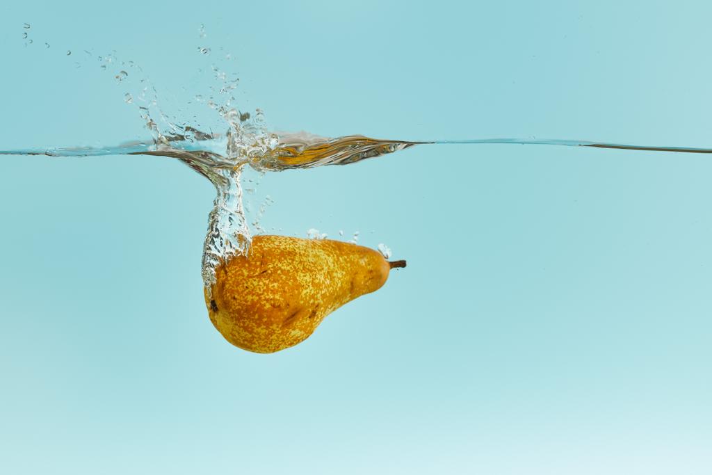 ripe pear falling deep in water with splash on blue background - Photo, Image