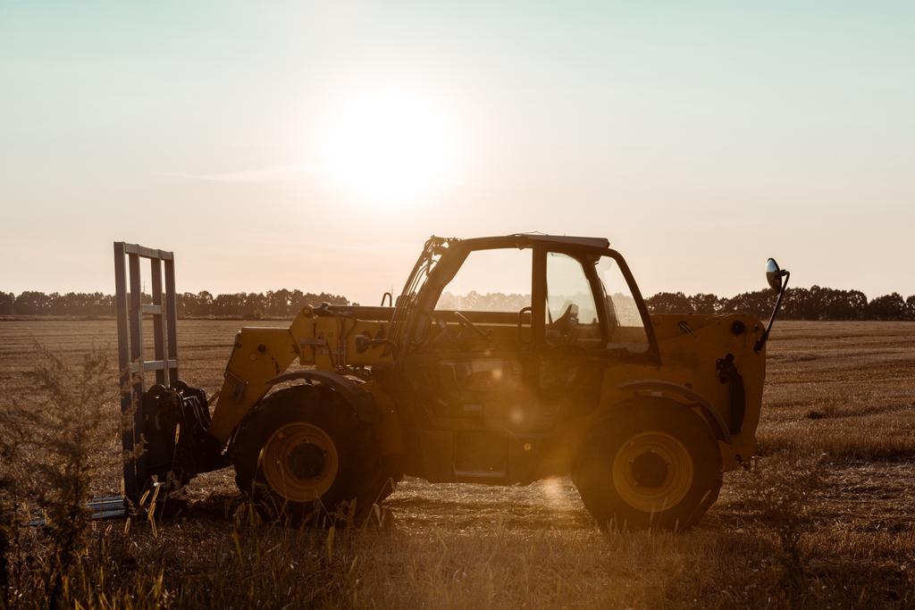 солнечный свет на тракторе возле пшеничного поля вечером
  - Фото, изображение