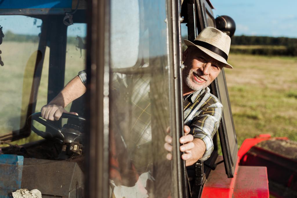 Selektiver Fokus des gut gelaunten Oberbauern am Traktor  - Foto, Bild