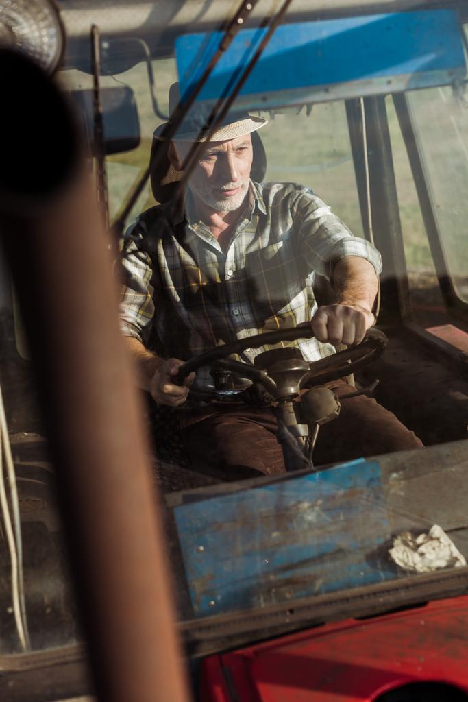 messa a fuoco selettiva del bel lavoratore autonomo che sorride mentre guida il trattore
  - Foto, immagini