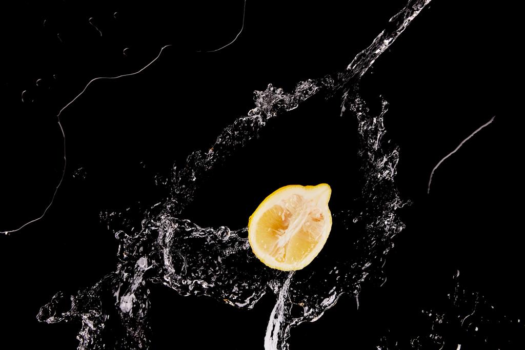 felső kilátás-ból érett citrom fél-val tiszta víz loccsanás elszigetelt-ra fekete - Fotó, kép