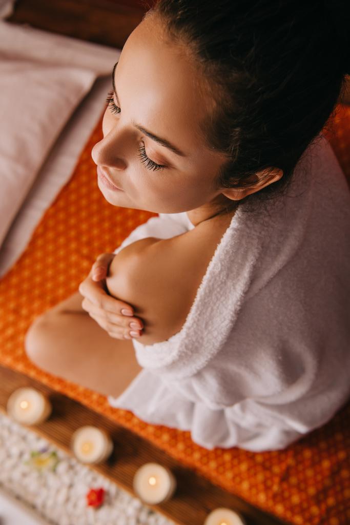 high angle view of attractive woman in bathrobe sitting on massage mat in spa salon - Photo, Image
