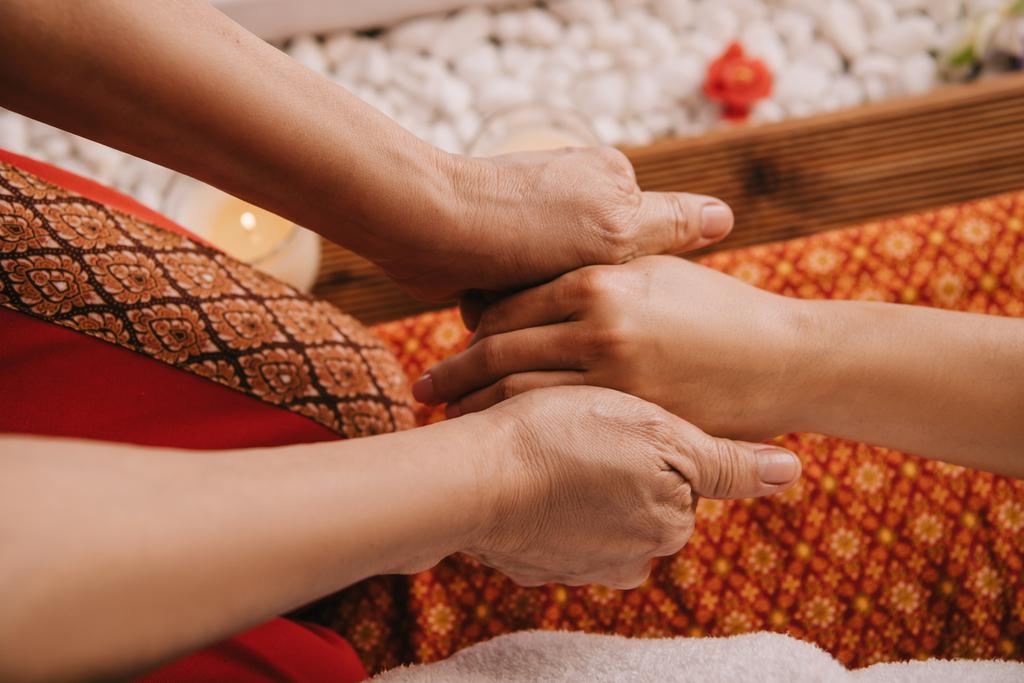 обрізаний вид масажиста робить масаж рук жінці в спа-салоні
  - Фото, зображення