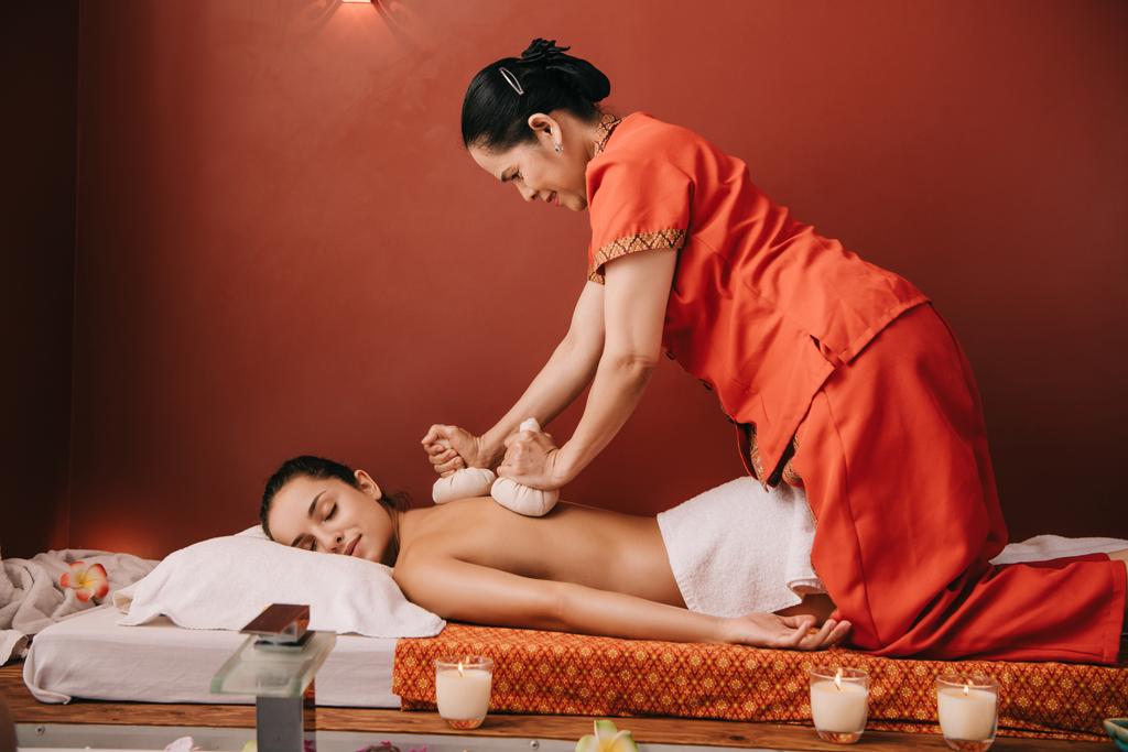 Aziatische masseur doet terug massage met kruiden ballen naar vrouw in Spa - Foto, afbeelding
