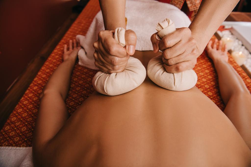 przycięte widok masażysta robi masaż pleców z ziołowych kulek do kobiety w spa - Zdjęcie, obraz