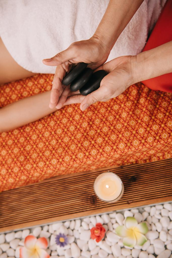 vista cortada de massagista segurando pedras quentes para massagem
  - Foto, Imagem