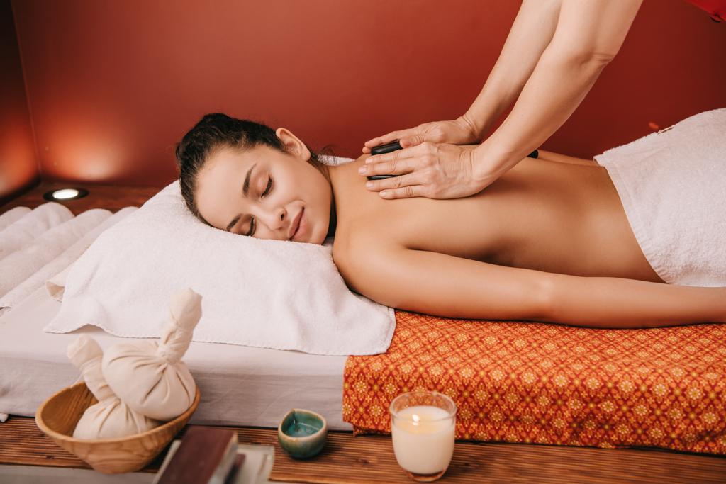 bijgesneden weergave van masseur doen Hot Stone Massage naar vrouw in Spa Salon  - Foto, afbeelding