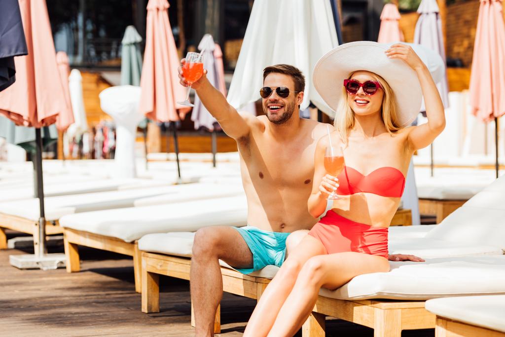 felice coppia sorridente che tiene cocktail al resort nella giornata di sole
 - Foto, immagini