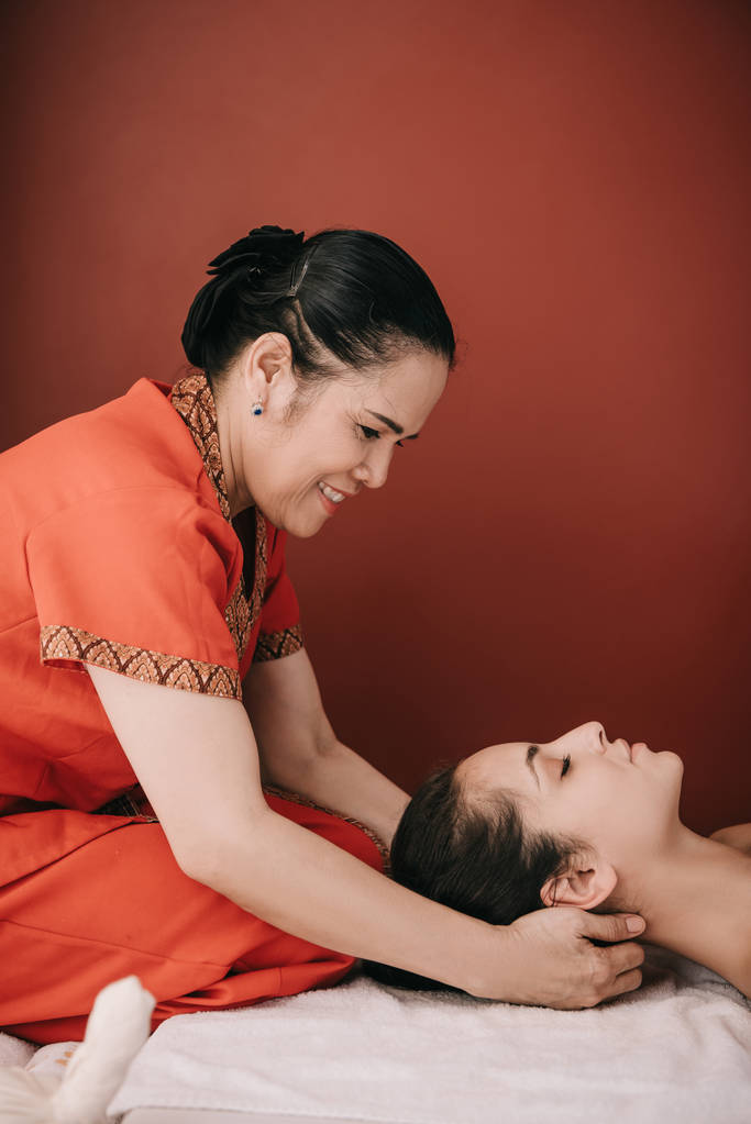 vista lateral do massagista asiático fazendo massagem no pescoço para mulher no salão de spa
  - Foto, Imagem