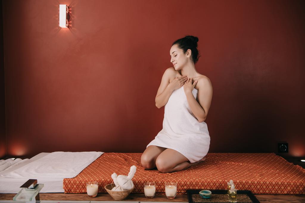 attraente donna con gli occhi chiusi in asciugamano seduta su tappetino da massaggio
  - Foto, immagini