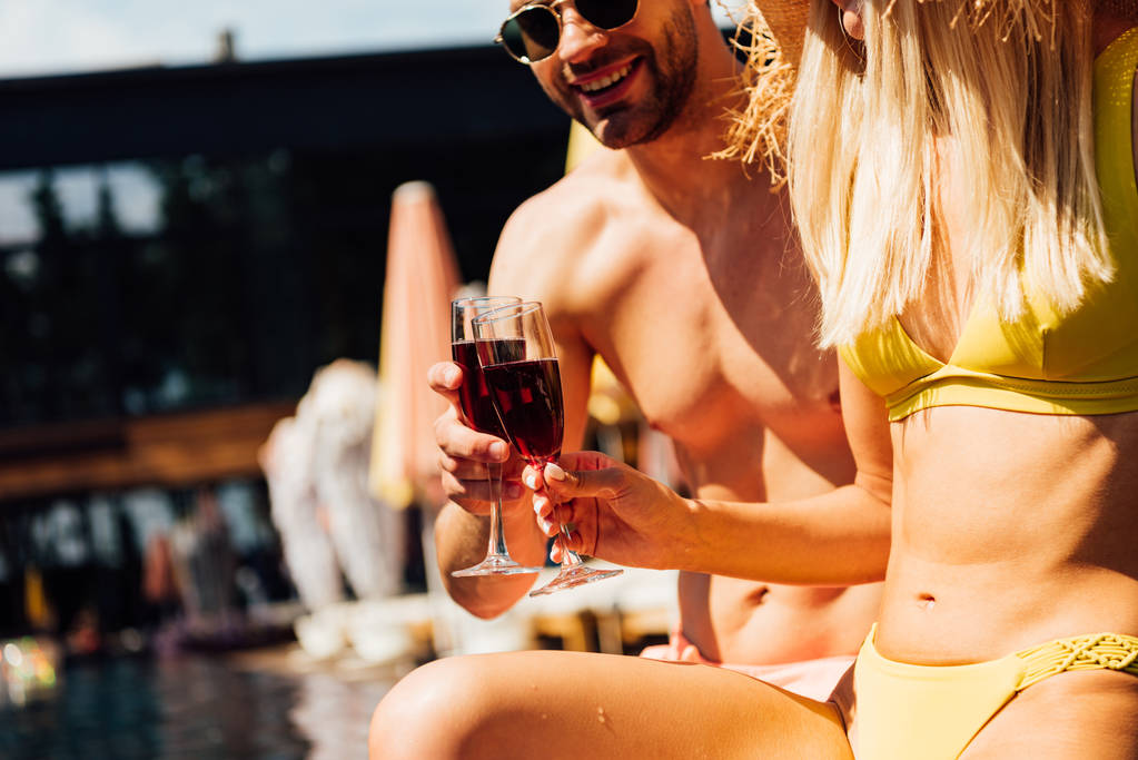 vue recadrée du couple sexy tenant des verres de vin rouge dans la piscine
 - Photo, image