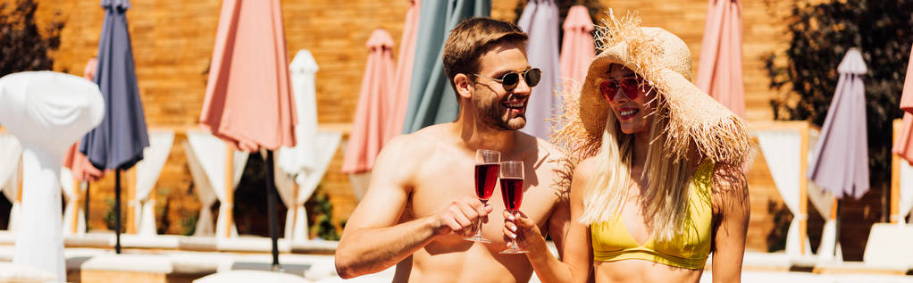 панорамный снимок сексуальной пары, держащей бокалы вина с красным вином на курорте
 - Фото, изображение