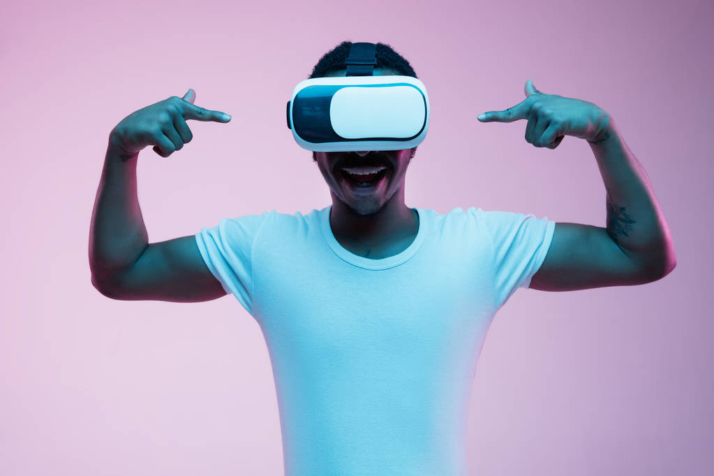 Молодий афро-американський чоловік використовує VR-окуляри в неоновому світлі
 - Фото, зображення