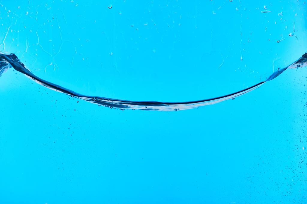 golvende transparant zoet water op blauwe achtergrond met druppels - Foto, afbeelding