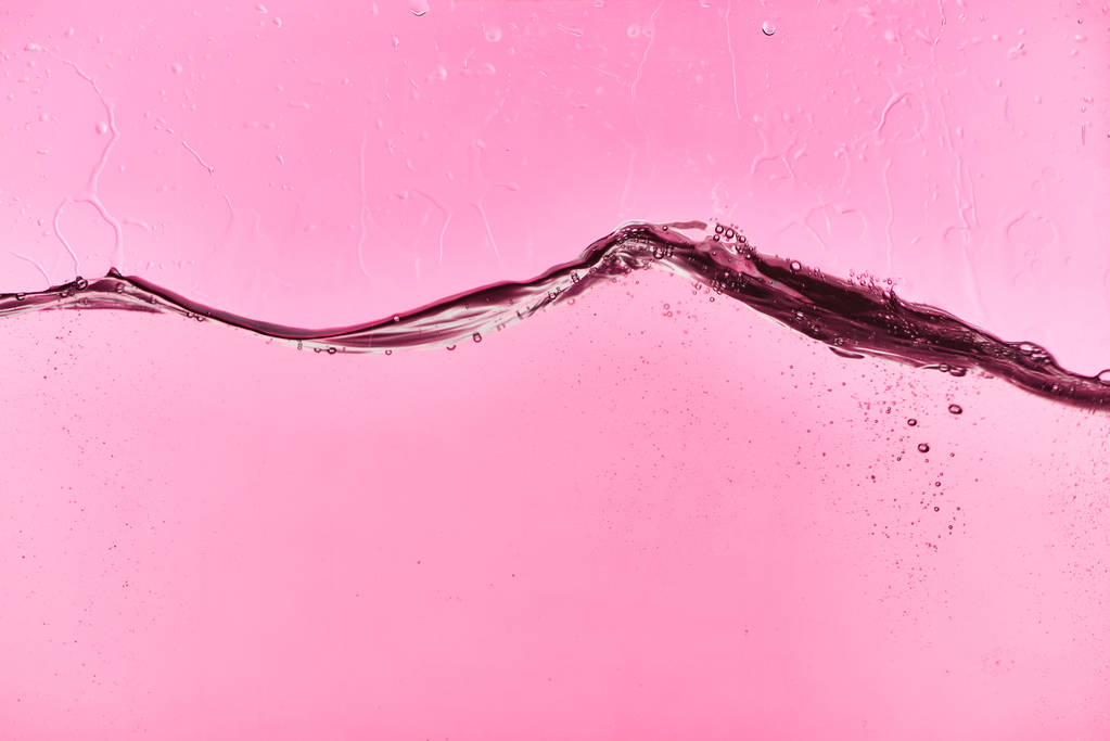 κυματιστά καθαρό φρέσκο νερό σε ροζ φόντο με σταγόνες και φυσαλίδες - Φωτογραφία, εικόνα