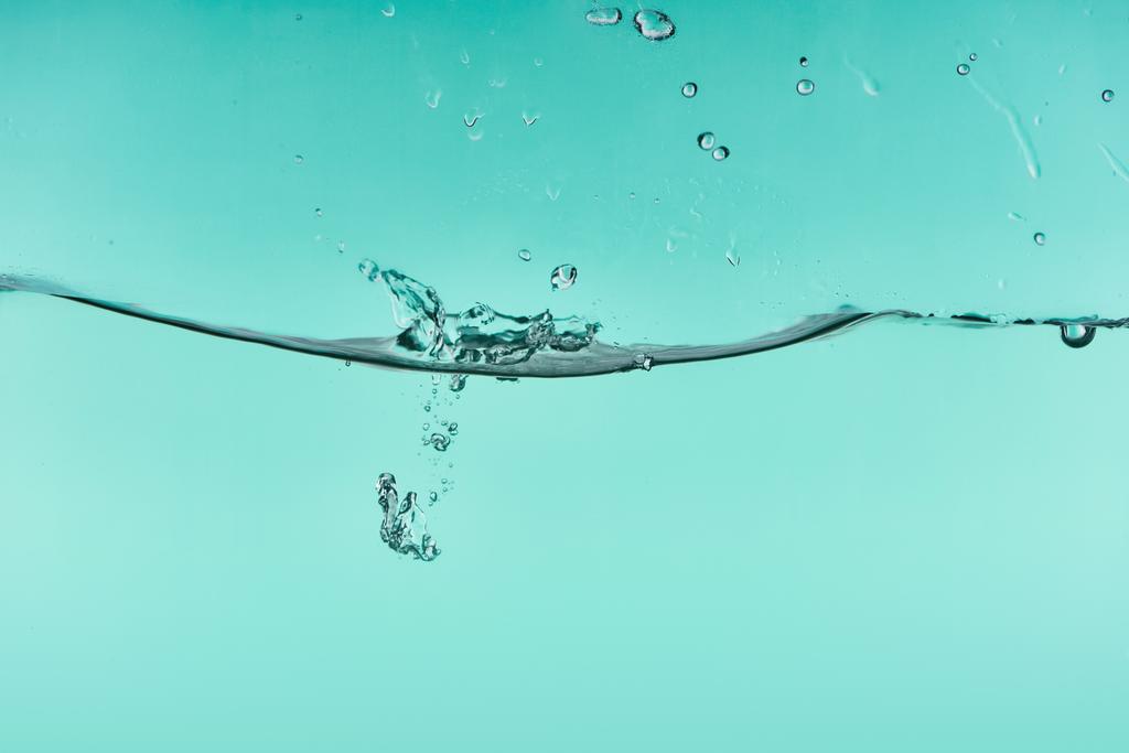 хвиляста прозора вода на бірюзовому фоні з бризками та бульбашками
 - Фото, зображення