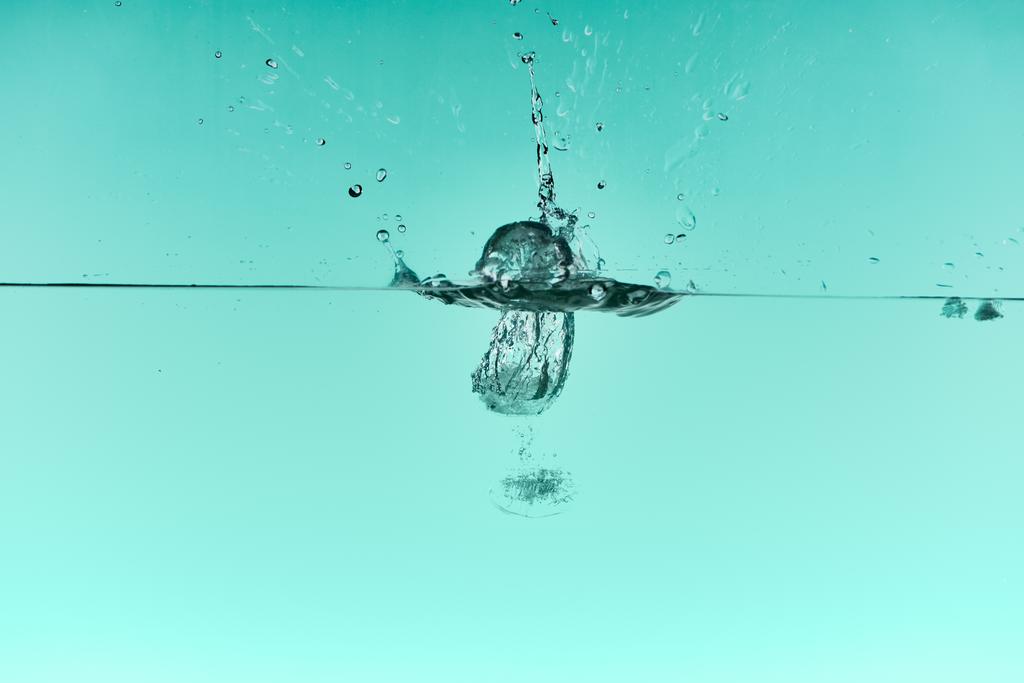 przezroczyste kostki lodu opadające głęboko w wodzie z Splash na turkusowym tle - Zdjęcie, obraz