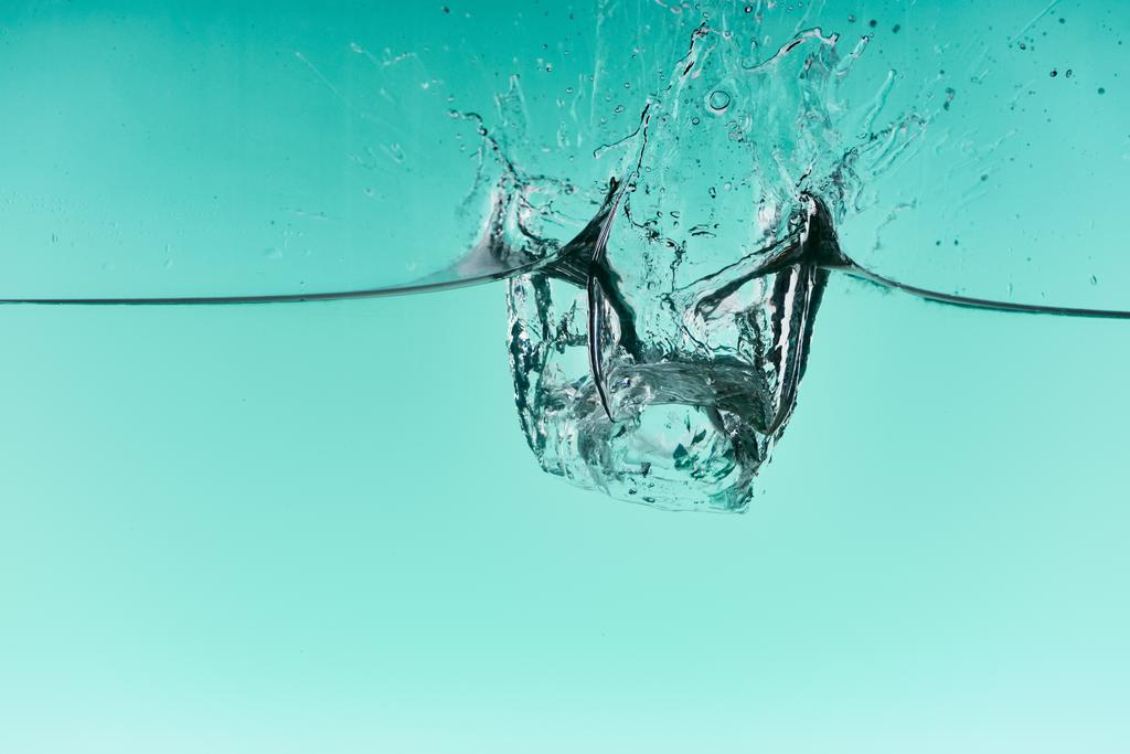 прозрачные кубики льда, падающие в воду с брызгами на бирюзовом фоне
 - Фото, изображение