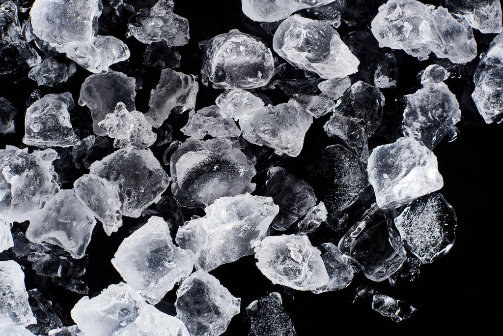 bovenaanzicht van smelt ijsblokjes geïsoleerd op zwart - Foto, afbeelding