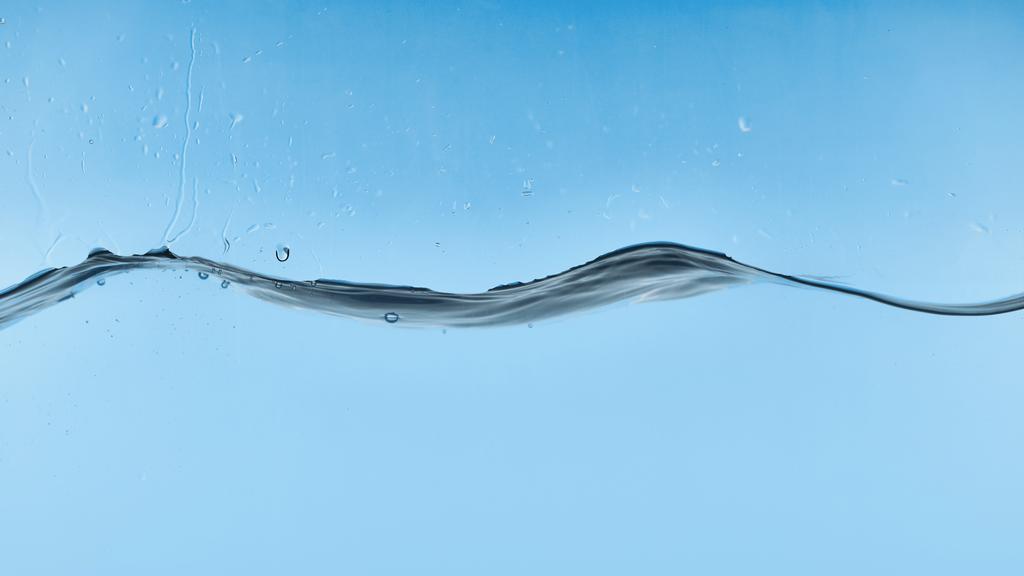 golvende transparant water op blauwe achtergrond met druppels - Foto, afbeelding