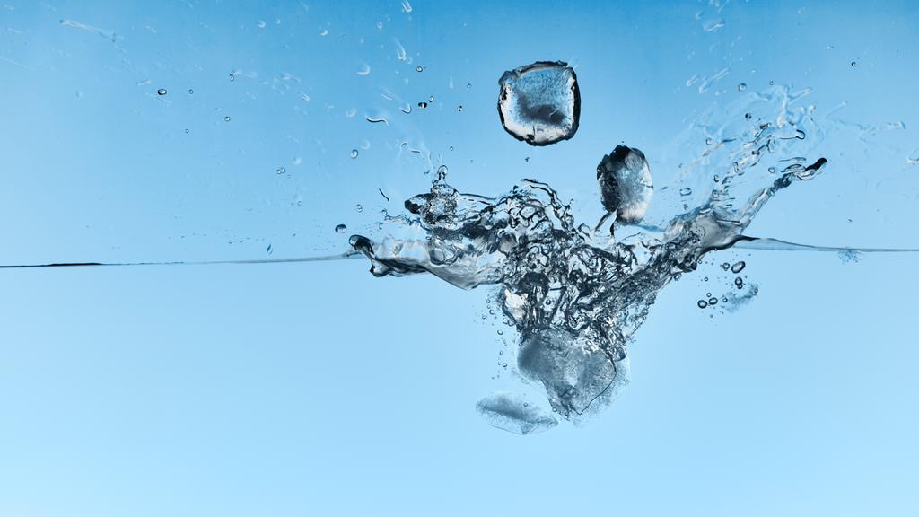 agua transparente con cubitos de hielo que caen y salpicaduras sobre fondo azul
 - Foto, Imagen
