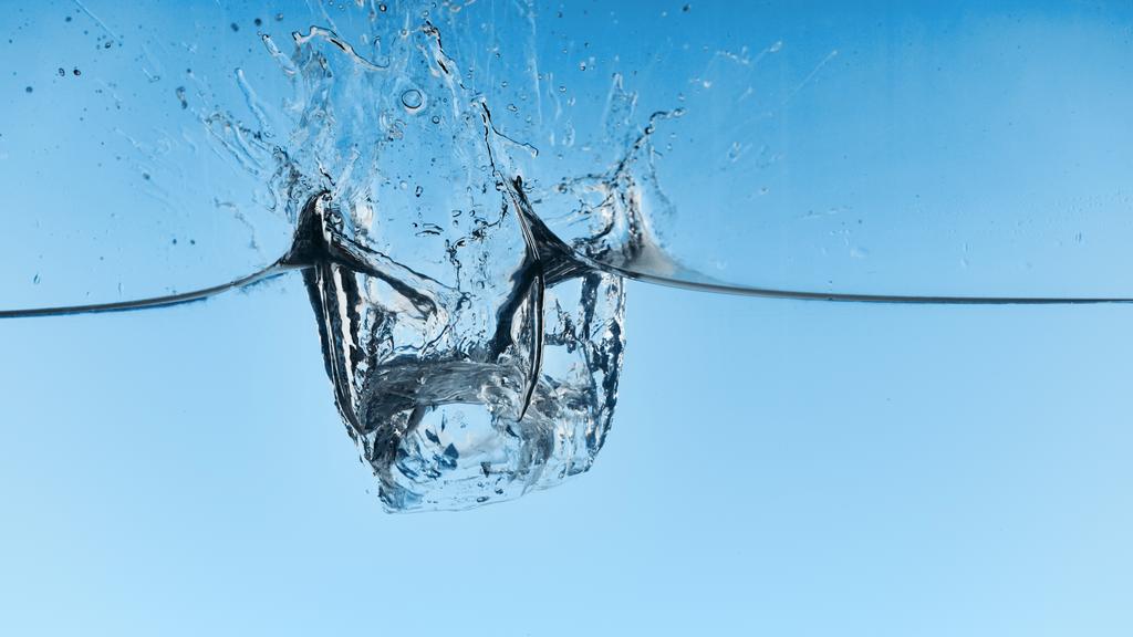 przezroczysta woda z opadającymi kostkami lodu i Splash na niebieskim tle - Zdjęcie, obraz