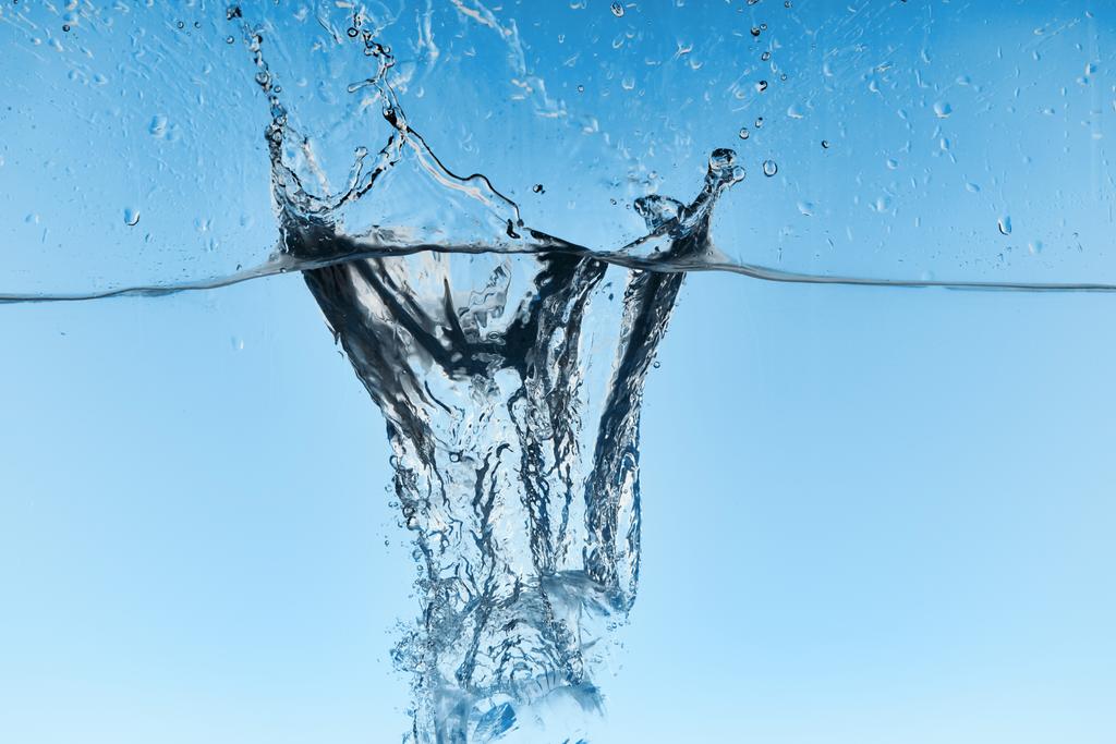 helder water met vallende ijsblokjes en Splash op blauwe achtergrond - Foto, afbeelding