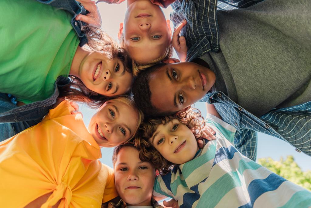 вид снизу счастливых мультикультурных детей, смотрящих в камеру
  - Фото, изображение
