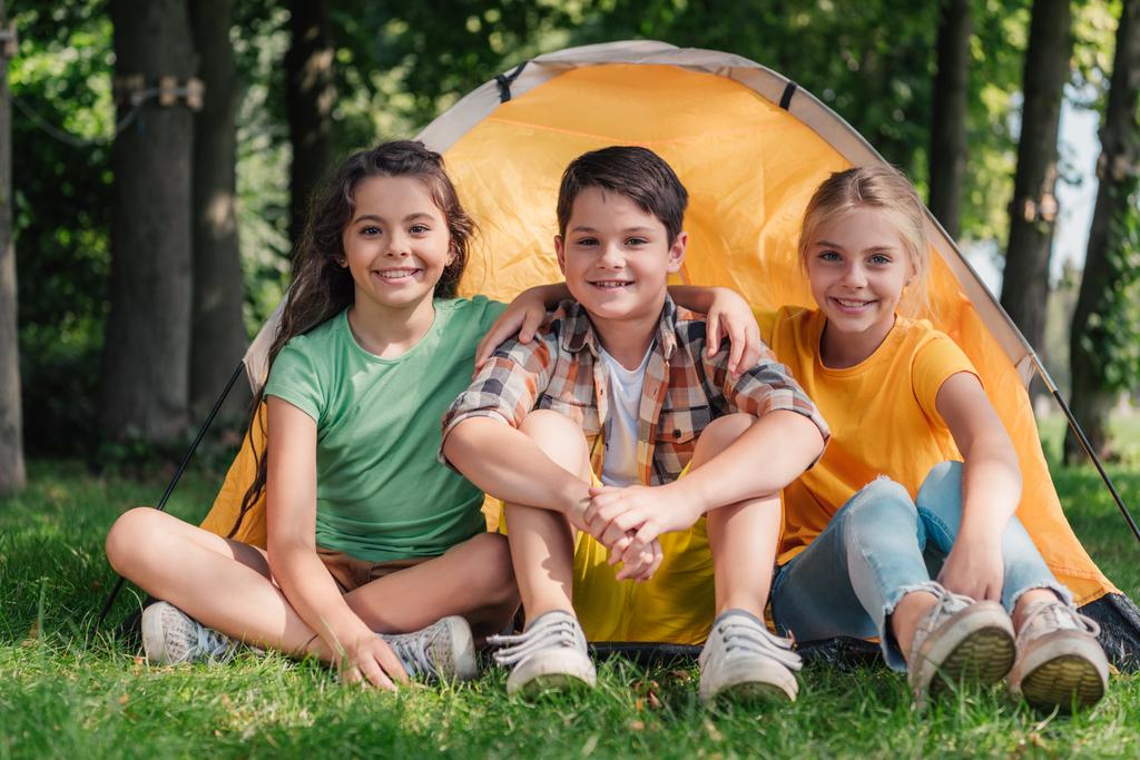kamp yakınında sevimli arkadaşlar ile oturan mutlu çocuk  - Fotoğraf, Görsel