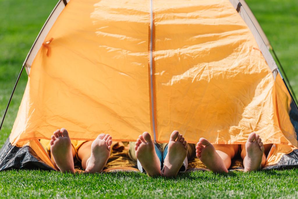 cropped view of kids with barefoot lying in yellow camp  - Photo, Image