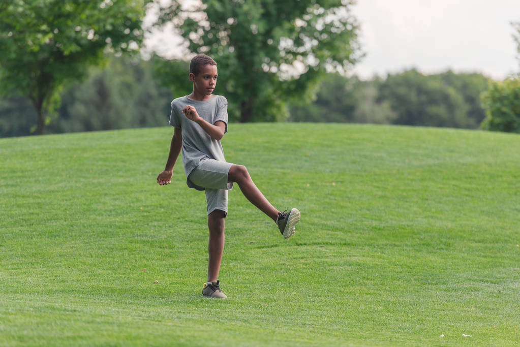 草の上で運動かわいいアフリカ系アメリカ人の少年  - 写真・画像