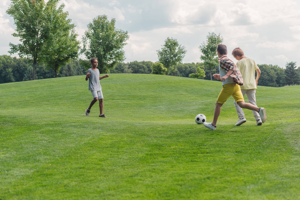 милий афроамериканський хлопчик дивиться на друзів, граючи в футбол
  - Фото, зображення