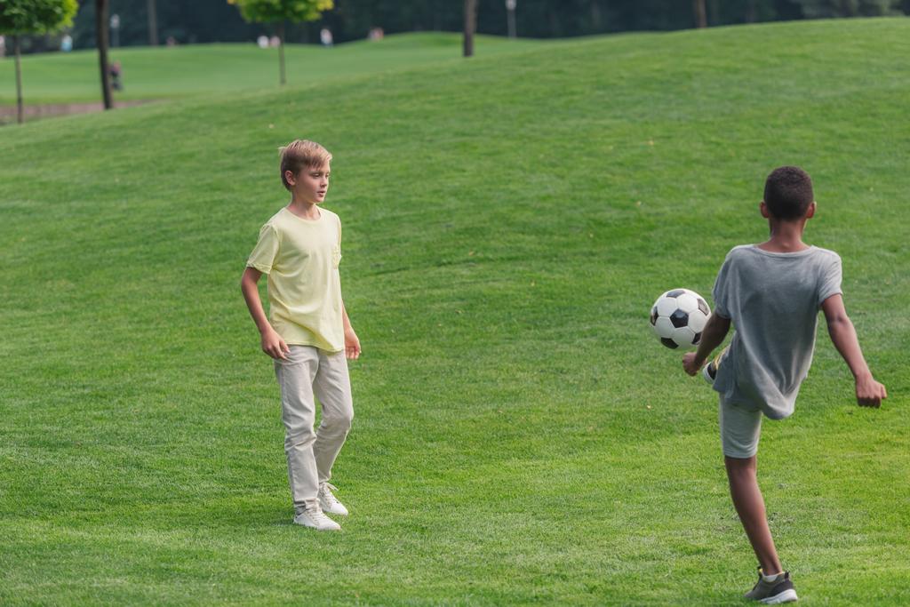 Niedliche multikulturelle Kinder spielen Fußball auf Rasen  - Foto, Bild