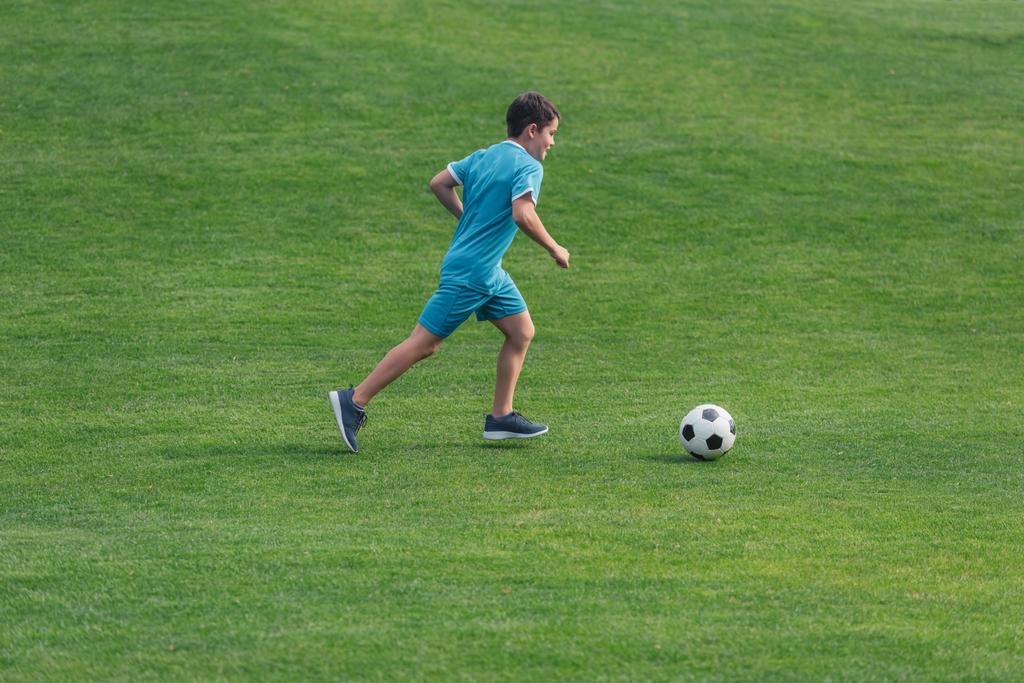 gyerek a Sportruházat futó zöld fű a labdarúgás  - Fotó, kép