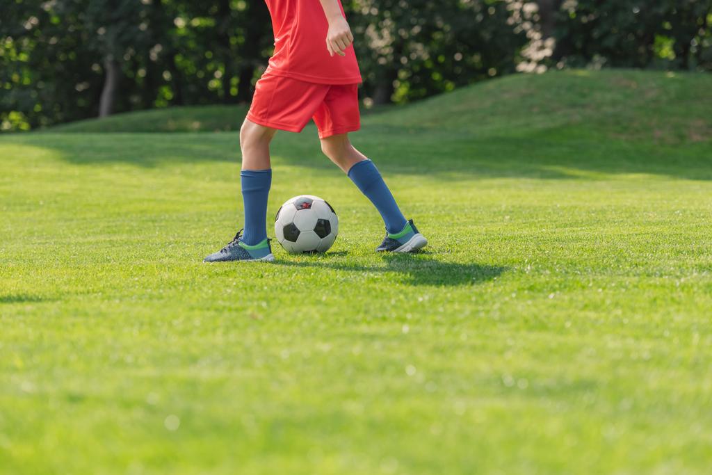 enfoque selectivo del niño en ropa deportiva roja jugando fútbol
  - Foto, Imagen