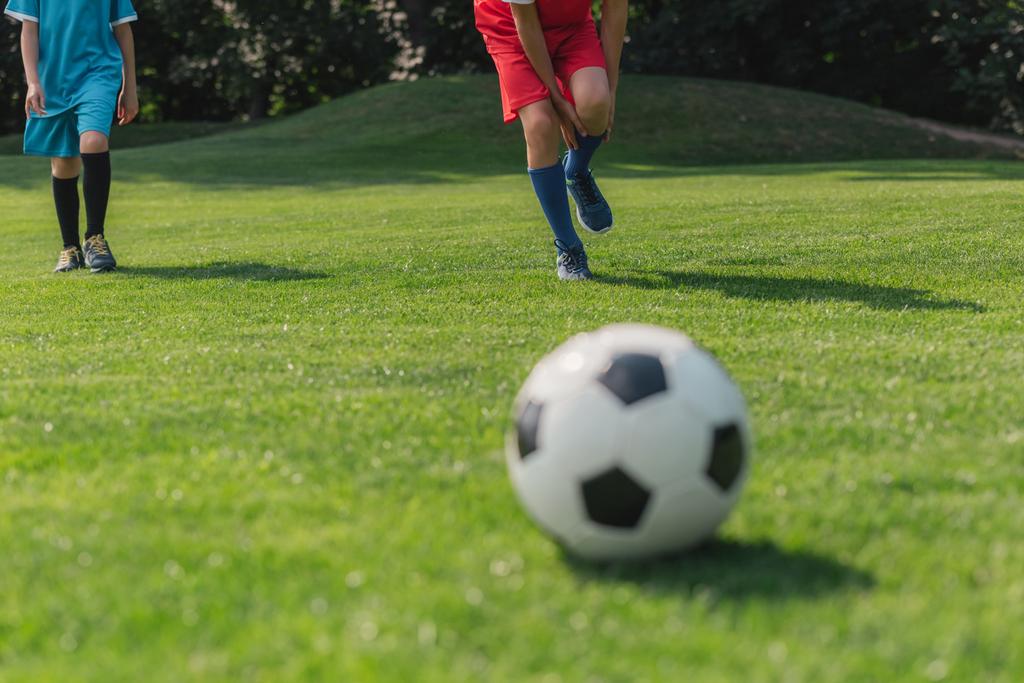 селективный фокус мальчика касаясь ноги рядом друг рядом с футболом
  - Фото, изображение