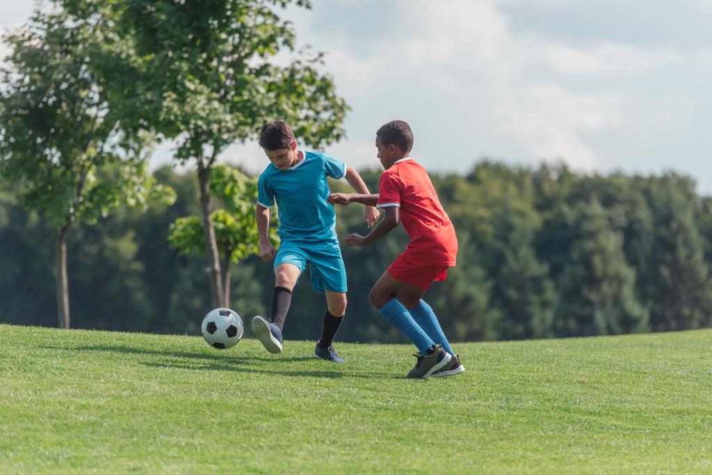 милые мультикультурные дети играют в футбол на траве
  - Фото, изображение