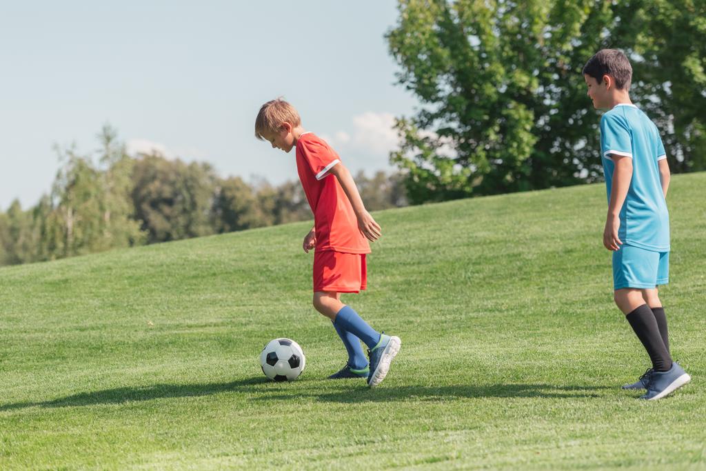 amis en vêtements de sport jouer au football sur l'herbe
  - Photo, image