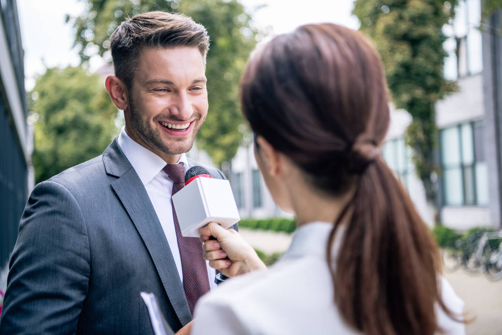 journaliste tenant un microphone et parlant avec un homme d'affaires en tenue de cérémonie
  - Photo, image