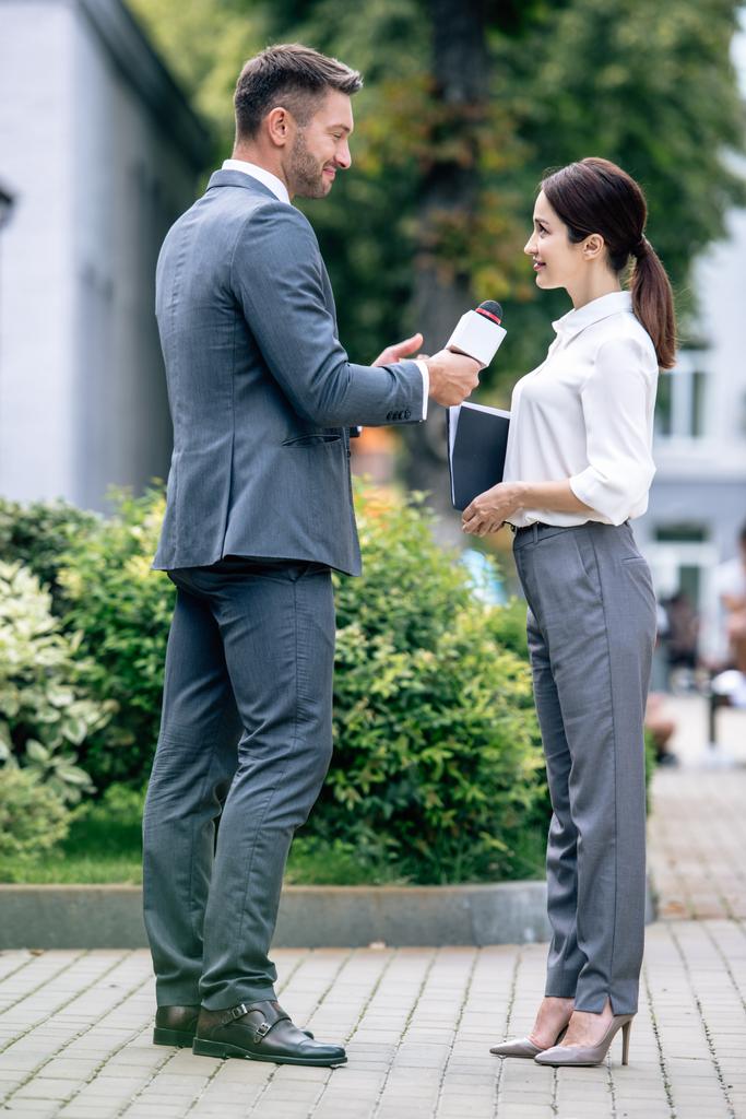 журналист держит микрофон и разговаривает с бизнесвумен в формальной одежде
  - Фото, изображение