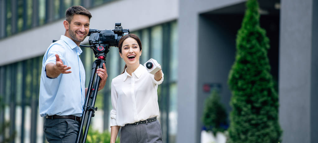 Panoramaaufnahme eines attraktiven Journalisten mit Mikrofon und Kameramann mit digitaler Videokamera - Foto, Bild