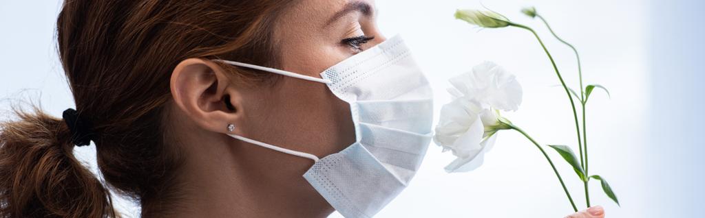 Panoramaaufnahme einer Frau in medizinischer Maske, die nach Blumen riecht  - Foto, Bild