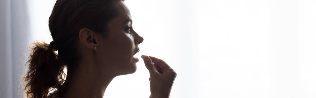 tiro panorâmico de mulher atraente tomando pílula em casa
  - Foto, Imagem