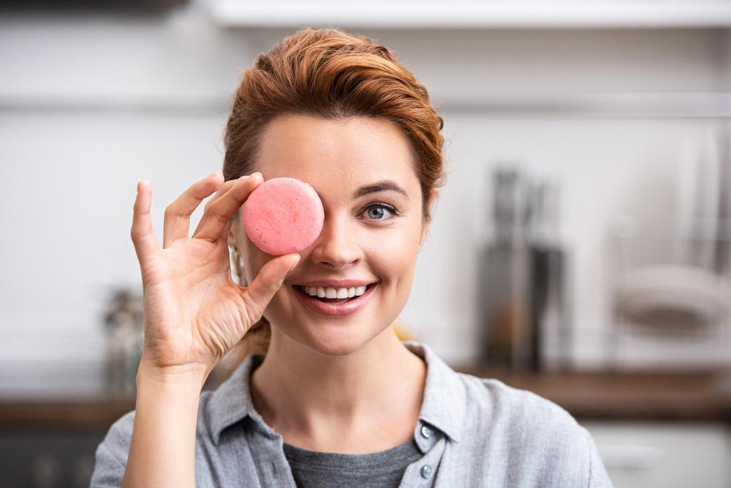 femme heureuse couvrant l'oeil avec du macaron doux
  - Photo, image