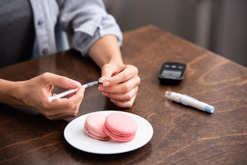 vue recadrée d'une femme tenant une seringue près d'un dessert sucré et d'une lancette sanguine
  - Photo, image