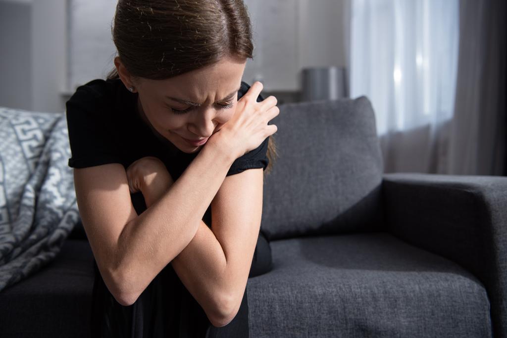 расстроенная женщина сидит на диване и плачет дома
 - Фото, изображение