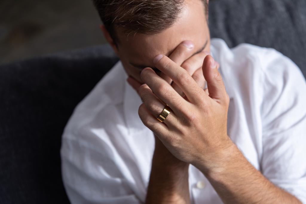 hombre deprimido con anillo llorando y cubriendo la cara con las manos en casa
 - Foto, Imagen
